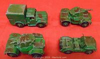 Four green and brown camouflage painted military toy vehicles on red surface, showing condition and types