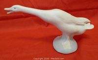 Front and side profile of the white matte duck figurine on a red background