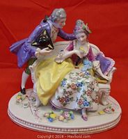 Front view showing man and woman seated with floral base and detailed coloring.