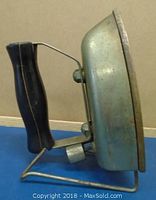Side view of vintage Westinghouse iron showing black handle and metal frame stand