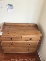 Front view of solid wood baby changing dresser showing two small top drawers and two large bottom drawers, natural wood finish with metal handles.