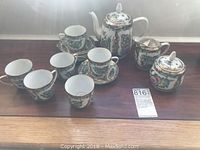 Full view of tea set with all components arranged on table, showing teapot, cups, creamer, sugar dish, and saucer.