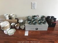 Full view of all tea sets and cups arranged on floor including boxed items.