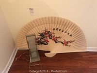 Modern table lamp base and large Japanese decorative fan leaning against wall on wood floor