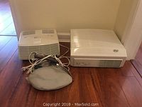 Two Hunter air filters placed side by side on wooden floor with a travel iron in front.