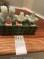 Three jade figurines each about 3 inches tall displayed on original green patterned boxes with red labels.