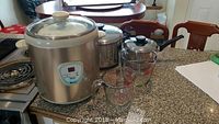 Overview of the rice cooker, cooking pots, and Pyrex measuring cups on a kitchen counter