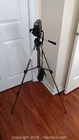 Kyocera Samurai X3.0 video camera mounted on tripod standing on wood floor.
