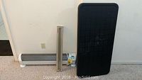 Honeywell baseboard heater parts and black plastic folding table shown vertically leaning against wall