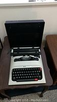 Full view of Olivetti Lettera 12 typewriter inside open black carrying case on small table