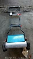 Full view of Gardena 380 C rotary mower showing handle, blue metal cover, wheels, and mower body.