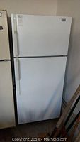 Full front view of the white Moffat refrigerator with two doors, top freezer, showing general soiling and wear.