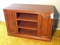 Front view of the oak entertainment center showing the two closed doors and two open shelves in the center section.