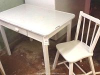 Full view of white vintage wooden table with enamel top and matching wooden chair.