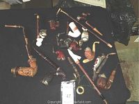 Overview of twelve assorted wooden and ceramic tobacco pipes laid out on black cloth