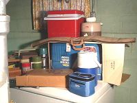 Overview of all items including coolers, thermoses, beverage dispenser, box for air mattress, and gun case