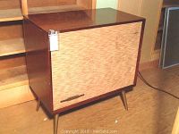 Full view of RCA Victor stereo wood cabinet with woven fabric front and angled legs, showing overall condition and dimensions.