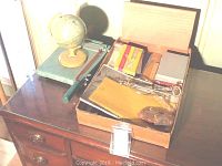 Full view of wooden dresser top with Premier paper cutter, globe, and packed box containing office items