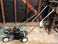 Side view of the Craftsman gas powered lawn edger showing wheels, engine, and blade.