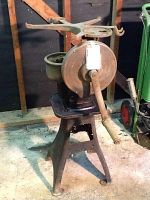 Full view of heavy steel antique machine on stand with large hand crank and top spool component.
