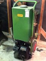 Full view of green metal mist sprayer with wheels and handle, showing overall size and shape.