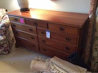 Full view of cherry wood dresser showing 9 drawers with decorative metal handles.