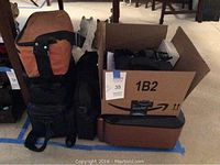 Photo of camera bags and carrying cases stacked together, including a large orange and black case.