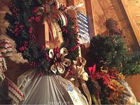 Wreath with red berries, pine cone, white pod accents next to other wreaths and wrapped items