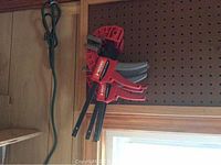 Red Husky quick-grip clamps hanging on pegboard.