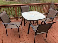 Full set of outdoor furniture showing one square glass-top table and four surrounding metal frame chairs with mesh seating.