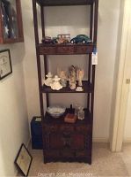 Full view of wooden shelving unit with various objects placed on shelves and drawers visible.