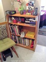 Full view of the front of the solid wood bookcase with various personal items on top and some books on shelves, showing minor wear.