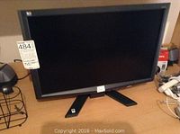 LG widescreen monitor with Windows Vista sticker on stand and visible on wooden desk.