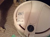 Close-up image showing the top of the white circular air filter with dial and sticker label.