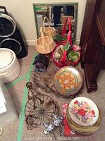 Photo showing the mirror, multiple woven baskets, floral arrangement in basket, decorative tins, wooden bird house, metal garden decorations including a wheel and animal figurines on the floor.