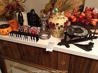 Various decorative items including a mechanical clock in pieces, wooden statues, pottery vase, and artificial flower arrangement on a wooden surface.