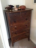 Full view of vintage wooden high boy chest with six drawers standing in corner.