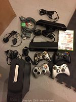 All components arranged on floor: console, Kinect sensor, controllers, cables, power supply, headset, game case.
