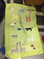 Green hooked rug with animal designs, light green background with checkered border.