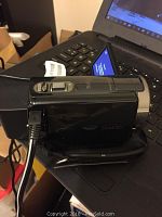 Side profile of the Sony Handycam with hand strap and attached USB cable