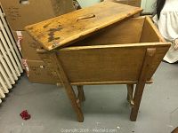 Side view of rustic wooden storage bench with lid open, showing interior storage compartment and four legs.