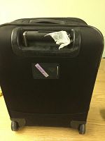 Back of black Victorinox wheeled luggage showing wear on handle and wheels.