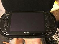 Sony PS Vita handheld gaming console inside a carrying case, front view showing screen and controls.