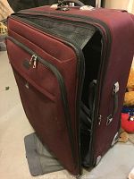 Red fabric TravelPro expandable suitcase partially opened showing inside compartment and garment bags with straps