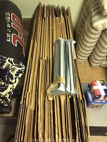 Flattened cardboard wardrobe boxes bundled alongside metal hanging rails on a storage floor.