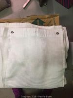Folded white waffle weave shower curtain showing metal grommets for hanging.