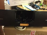 Front view of Sirius XM Universal Boombox speaker unit showing speaker grills, docking slot, and control buttons.