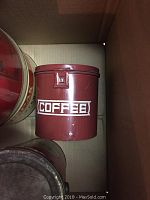 Red metal tin labeled 'COFFEE' in white text, cylindrical with clasp lid.