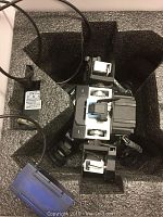 Ganker robot main unit seated in black foam tray with power adapter and blue storage box visible