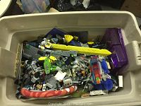 Full view of large plastic storage tub filled with mixed toys and LEGO pieces.